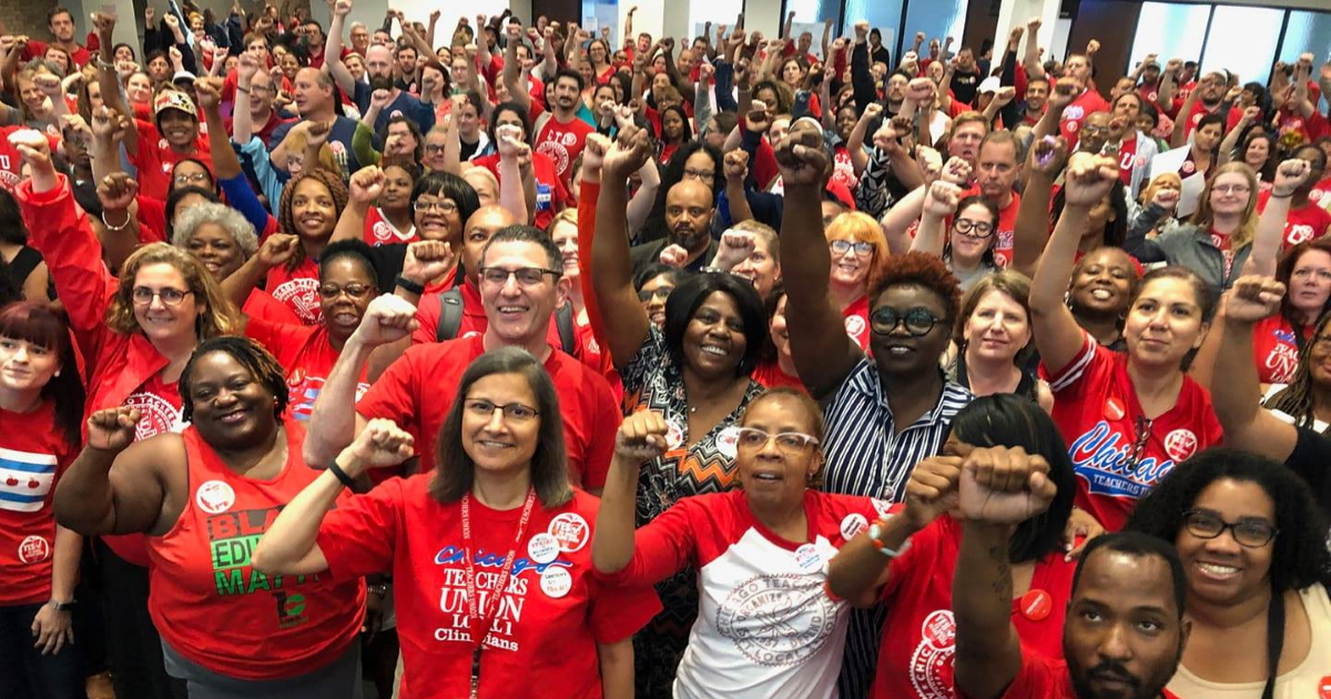 Hundreds of CTU members in red stand together with fists raised in solidarity in the main hall of the CTU Center.