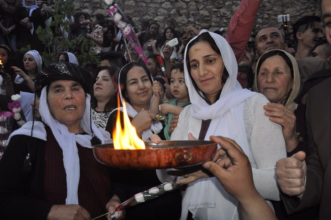 A photo showing Yazidi women and men celebrating their New Year festivities. One woman holds a burning candle. Other are dressed in traditional clothes. Image taken 13th April 2021. Credit: Darman Rosho Khalaf from the village of Ba’azra, Duhok. 